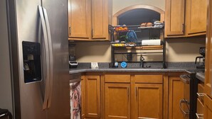 Una cucina con mobili in legno, un frigorifero in acciaio inossidabile, un forno a incasso e un microonde.
