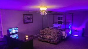 Una camera da letto con un letto a baldacchino, una scrivania con un computer, una sedia e una ventola a soffitto.