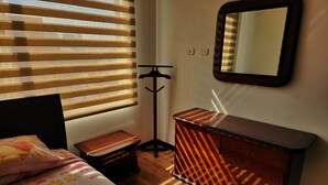 Un dormitorio con cama, cómoda, espejo y lámpara de pie.