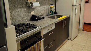 Una cocina con armarios de madera oscura, un refrigerador de acero inoxidable, una estufa a gas y un microondas.
