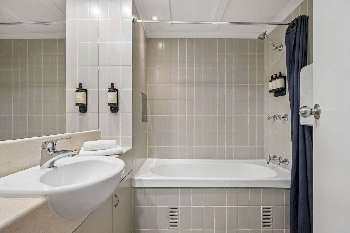 A bathroom with two sinks, a bathtub, and a shower.