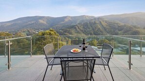 Una mesa con sillas en un balcón con vistas a un paisaje montañoso.