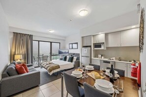 Une chambre d’hôtel moderne avec balcon, un coin repas et une kitchenette.