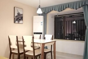 Un comedor con una mesa y sillas, una lámpara colgante, una ventana con rejas y un aire acondicionado de pared.