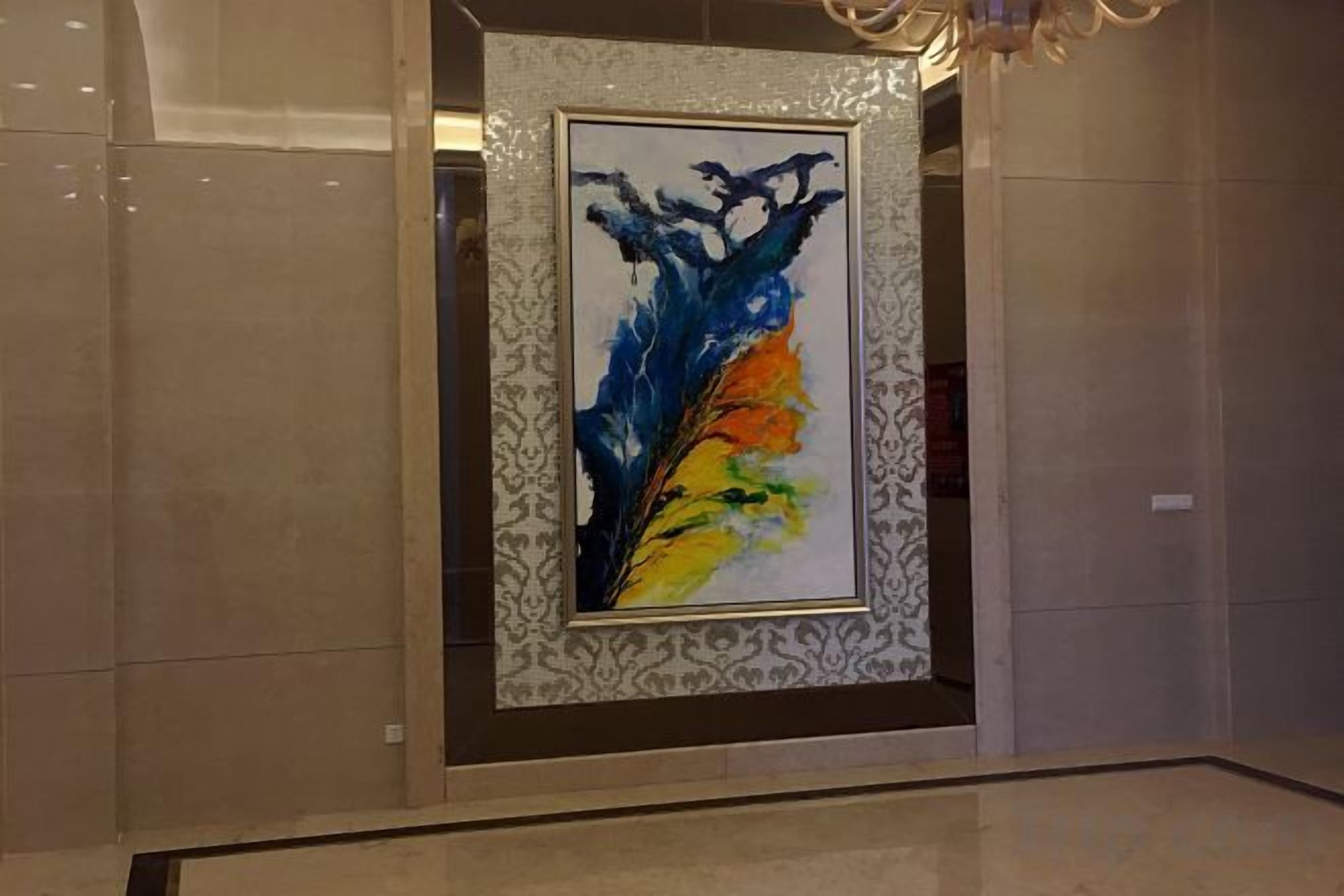 A framed abstract painting in a lobby with a patterned border.