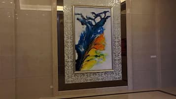 A framed abstract painting in a lobby with a patterned border.