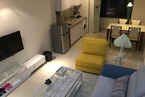 A compact living space with a kitchenette, a sofa, a dining table, and a television. - Lemon Heart Apartment Hotel (Foshan)