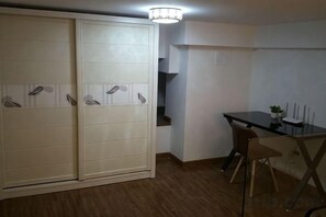 A room with a sliding door closet, a dining table with chairs, and a small potted plant. - Lemon Heart Apartment Hotel (Foshan)