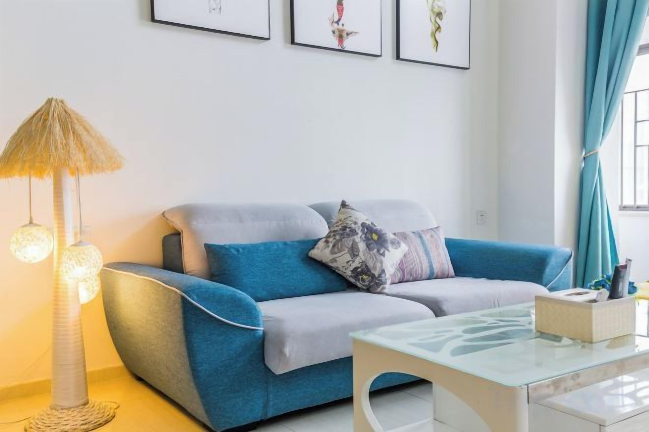 A modern living room with a blue sofa, a glass coffee table, and a unique lamp.