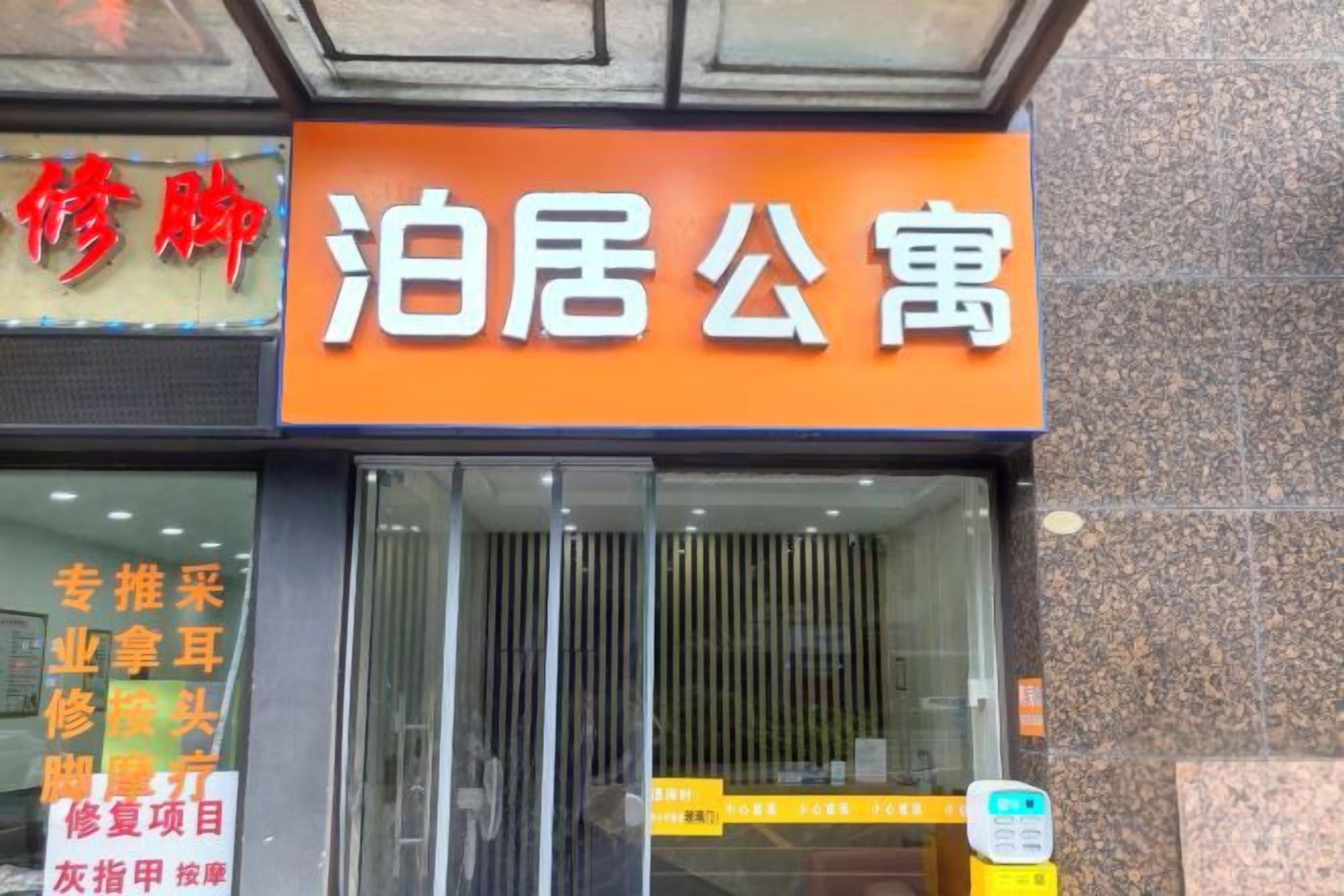 A hotel entrance with a prominent orange sign and a glass door.