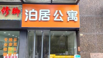 A hotel entrance with a prominent orange sign and a glass door.