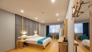 Quarto de hotel moderno com uma cama grande, mesas de cabeceira, uma escrivaninha e um espelho.
