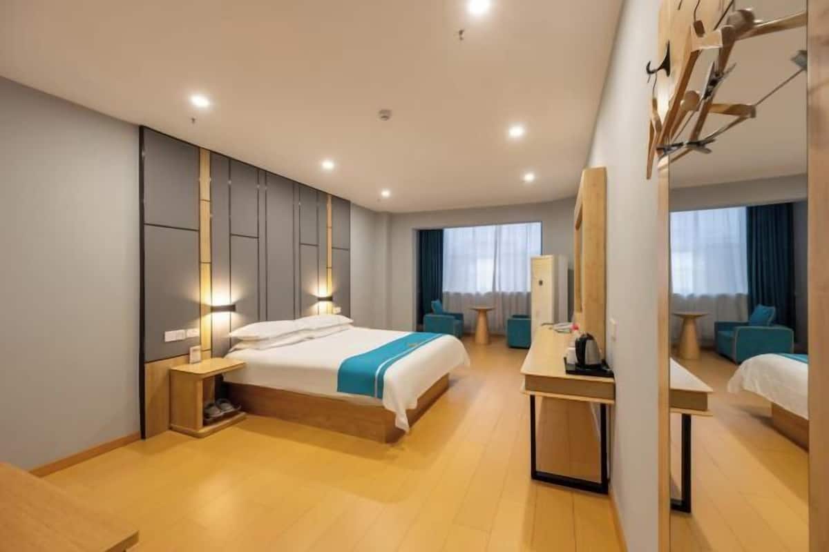 A modern hotel room with a large bed, bedside tables, a desk, and a mirror.