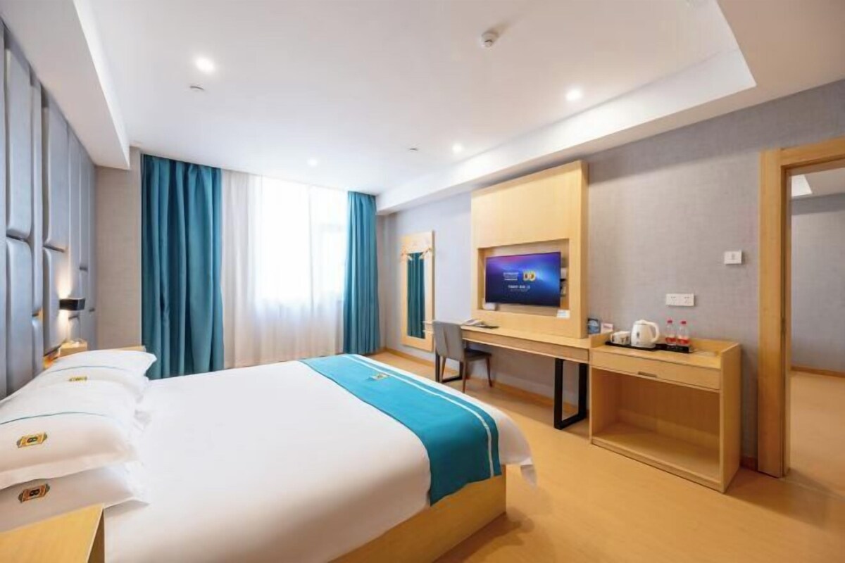 A hotel room with a bed, a desk, a television, and a wardrobe.