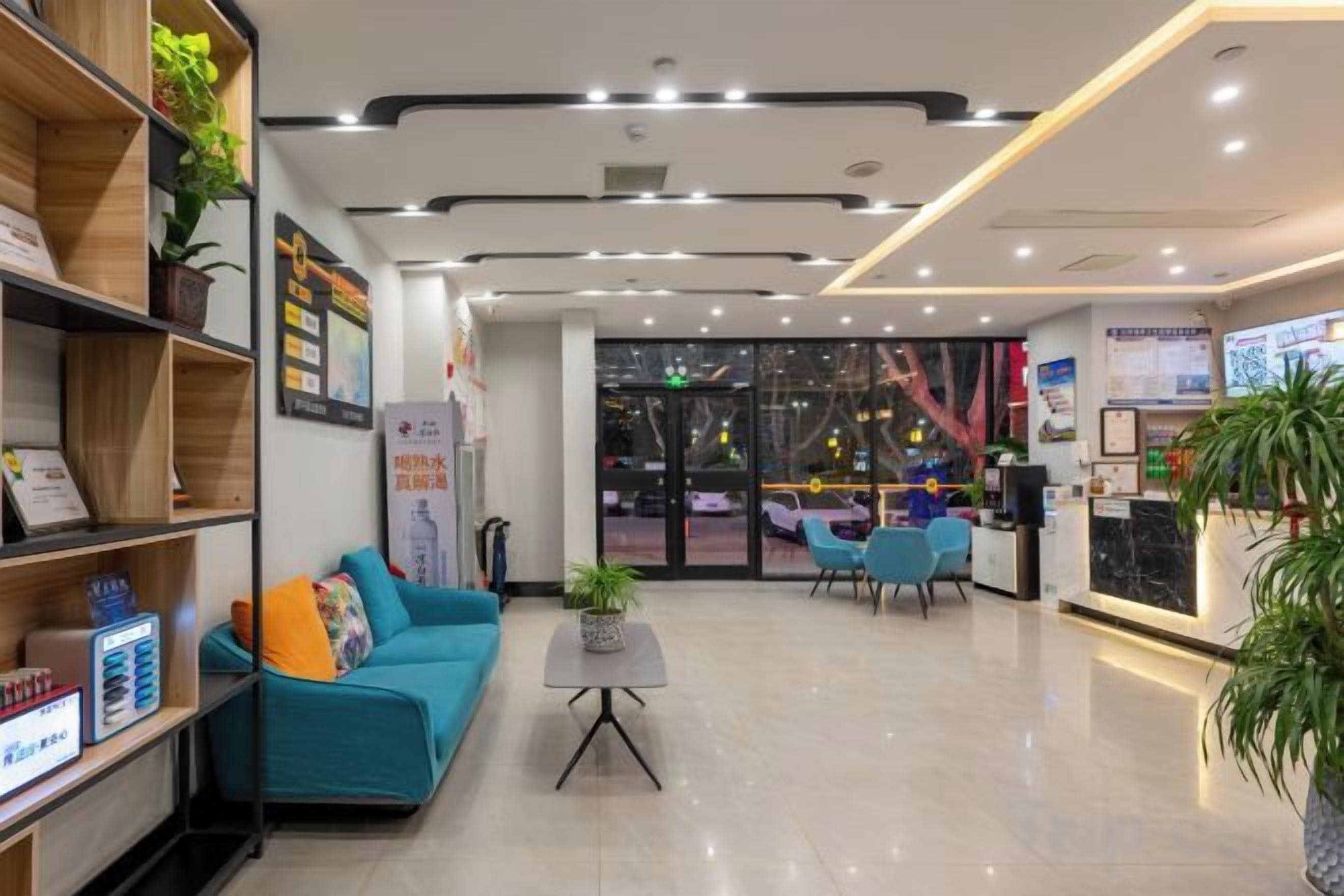 A modern lobby with a reception desk, seating area, and a staircase leading to an upper floor.