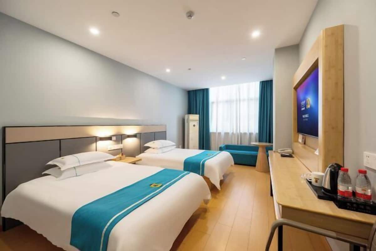 A hotel room with two beds, a desk, a TV, and a minibar.