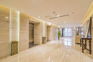 A spacious hotel lobby with a marble floor, a reception desk, and a large window.