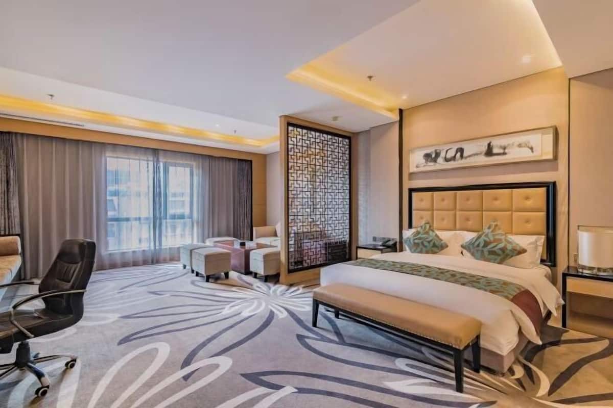 Una habitación de hotel con una cama grande, un escritorio, una silla, un sofá y un panel decorativo en la pared.