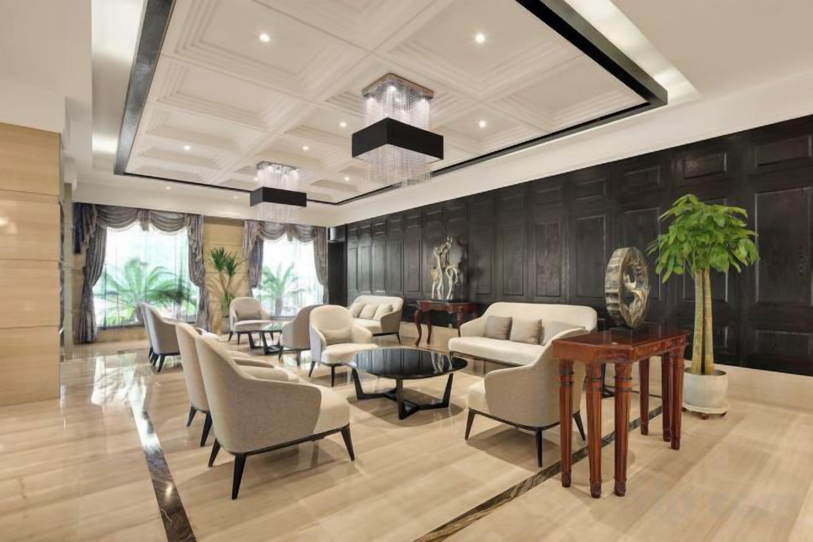 Un moderno hall de hotel con área de descanso, una mesa de centro y una planta grande.