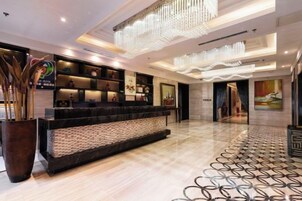 Un vestíbulo de hotel con mostrador de recepción, zona de estar y un candelabro.