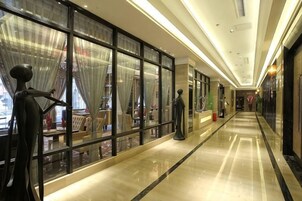 Un pasillo con puertas de vidrio, un maniquí y un piso pulido.