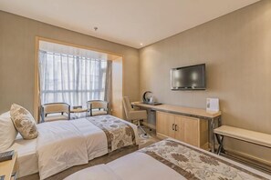 Habitación de hotel con dos camas, un escritorio, una silla, un televisor y una ventana con cortinas.