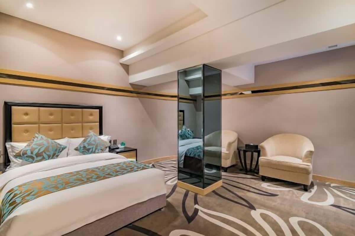 Un dormitorio con cama, una silla, una mesita de noche y un panel de vidrio.