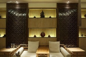 A traditional room with a wooden partition, shelves with decorative items, a cushioned seating area, and a small table. - Ziyu International Holiday Hotel (Chengde)
