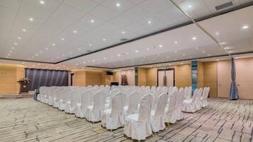 A large conference room with rows of white chairs, a podium, and a carpeted floor.