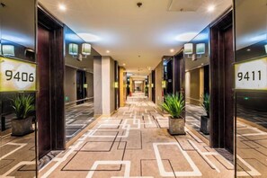 A hotel corridor with mirrored walls, numbered doors, and potted plants. - Ziyu International Holiday Hotel (Chengde)