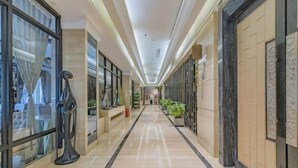A hallway with a marble floor, glass doors, and a black sculpture. - Ziyu International Holiday Hotel (Chengde)