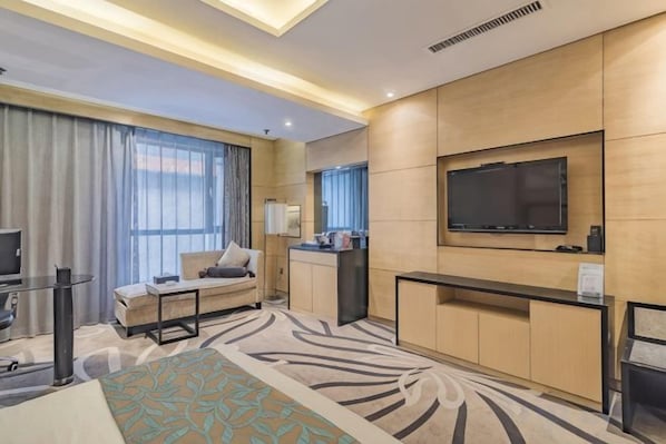 A hotel room with a bed, a desk, a TV, and a large window with curtains.