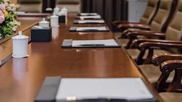 A conference table with a notebook, pen, and a small white container, likely for tea or coffee.