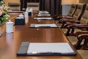 Una mesa de conferencias con un cuaderno, un bolígrafo y un pequeño recipiente blanco, probablemente para té o café.