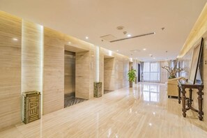A hotel corridor with marble flooring, a reception desk, and a large window. - Ziyu International Holiday Hotel (Chengde)