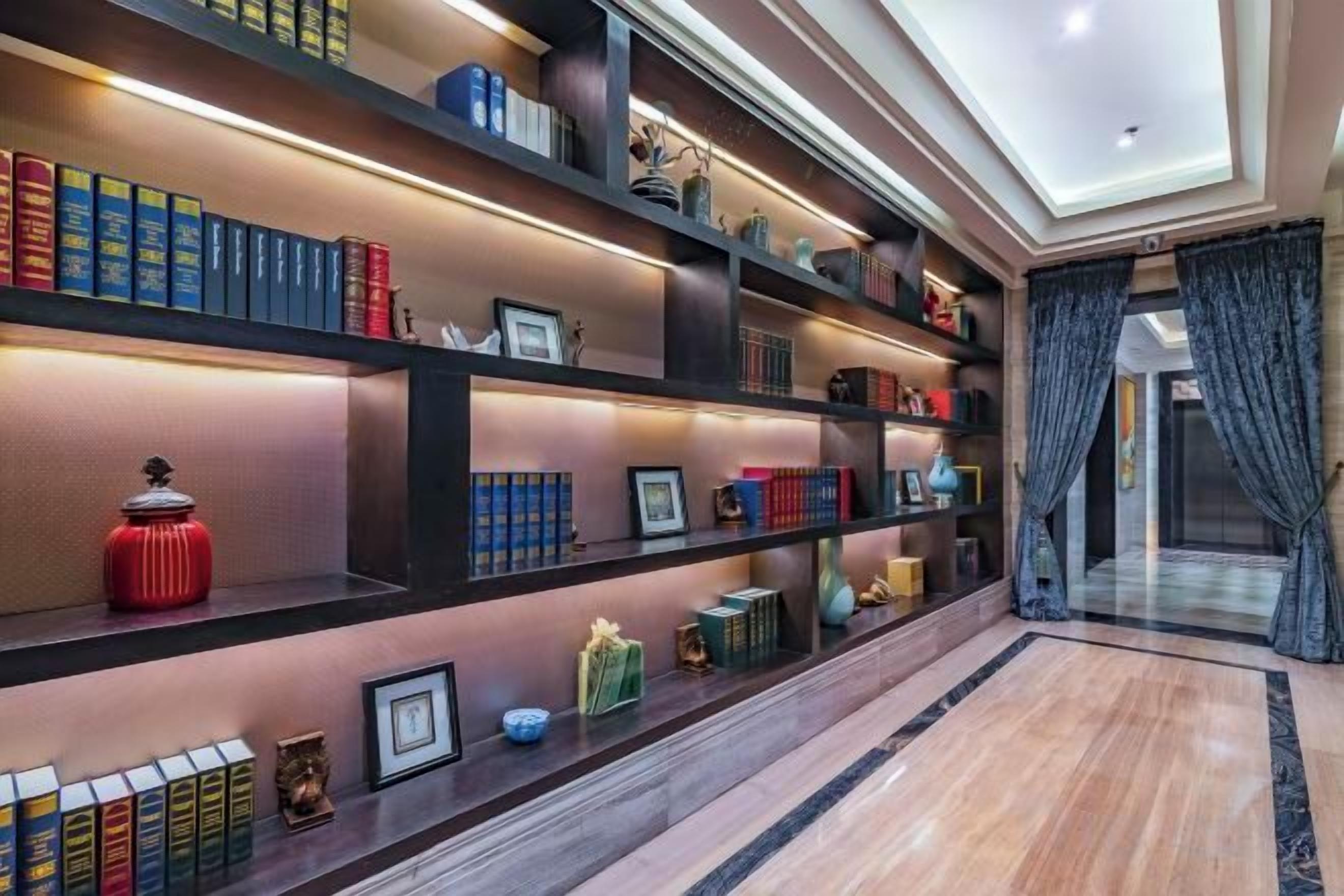 A hallway with bookshelves, a red vase, and a framed picture.