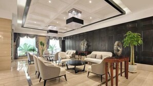 A spacious lobby with a high ceiling, modern furniture, and a large plant. - Ziyu International Holiday Hotel (Chengde)