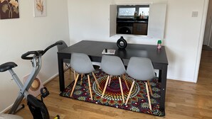 Ein kompakter Wohnbereich mit Esstisch, drei Stühlen, einem kleinen Fenster und einem farbenfrohen Teppich.
