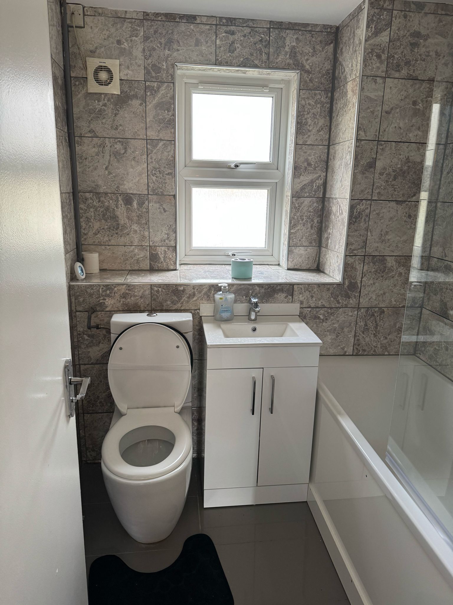 Een badkamer met toilet, wastafel en raam.