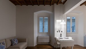 Een moderne woonkamer met een witte bank, een eettafel met stoelen en een ingebouwde airconditioning.