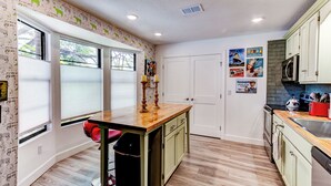 A kitchen with a wooden island, white cabinets, and a tiled backsplash.