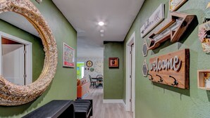 A hallway with a wooden bench, a large decorative mirror, and a welcome sign.