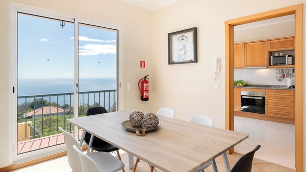 Un espace repas comprenant une table, des chaises et une vue sur la mer.