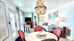 Zona pranzo con tavolo rotondo, sedie imbottite rosse e un lampadario.