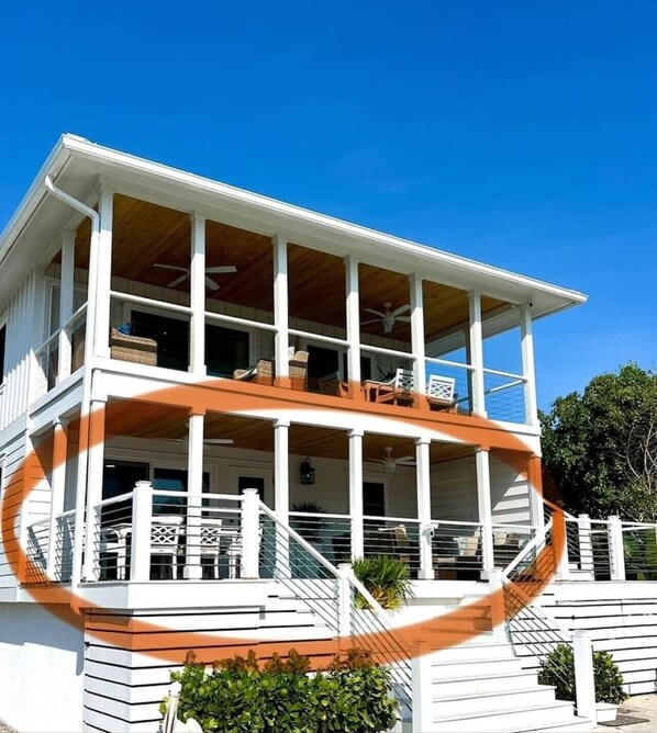 Una casa de dos pisos con balcón, fachada blanca y terraza de madera.