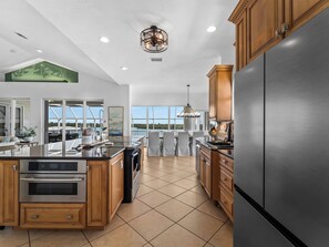 A modern kitchen with a large island, stainless steel appliances, and a view to the outside. - Bayfront home - Dock and Pool 3/3 (Englewood)