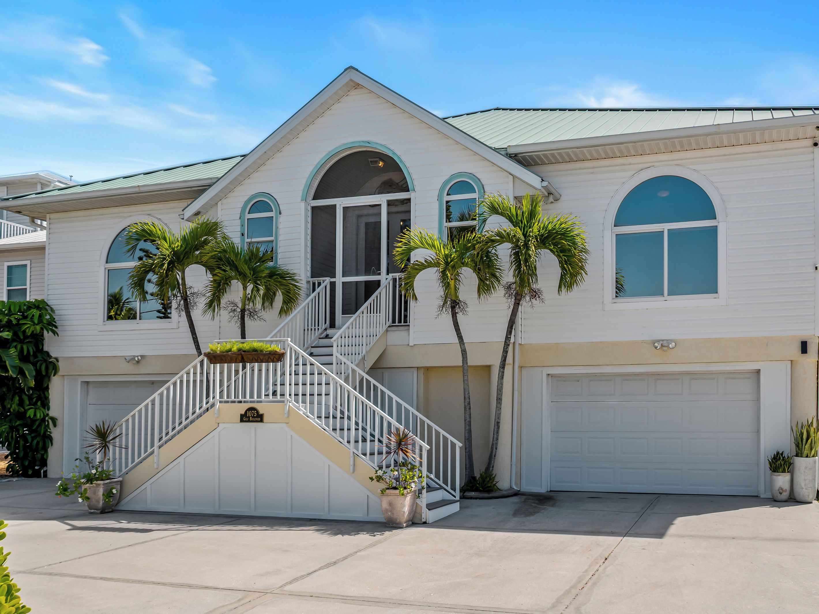 A two-story house with a white exterior, a front porch, and a garage.