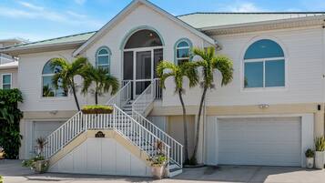 A two-story house with a white exterior, a front porch, and a garage.