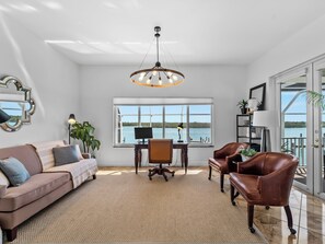 A spacious living room with a large window, a modern chandelier, and leather furniture. - Bayfront home - Dock and Pool 3/3 (Englewood)