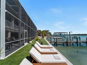 A poolside area with lounge chairs and a view of the water. - Bayfront home - Dock and Pool 3/3 (Englewood)